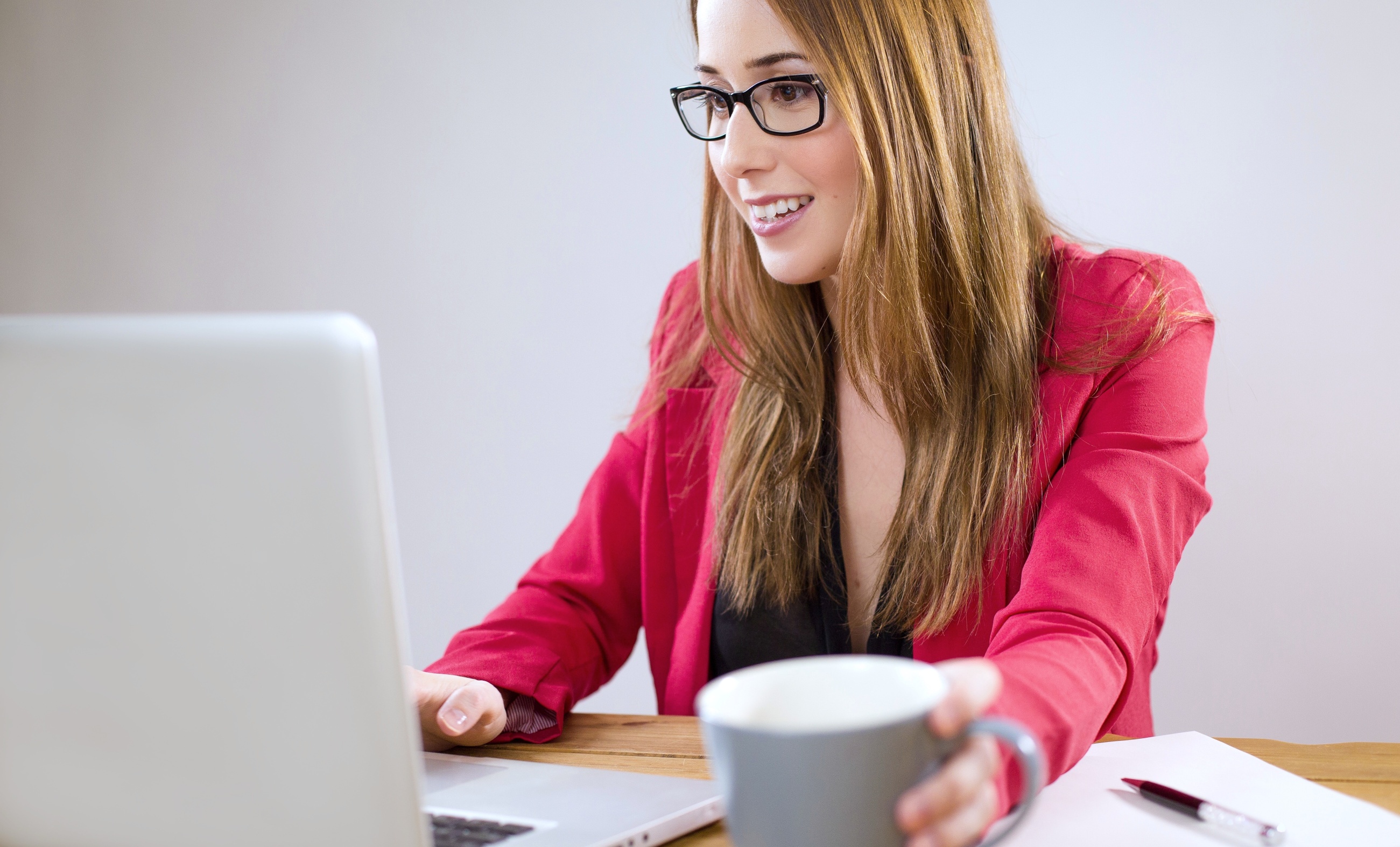 Žena čte nebo píše na počítači a usmívá se u toho